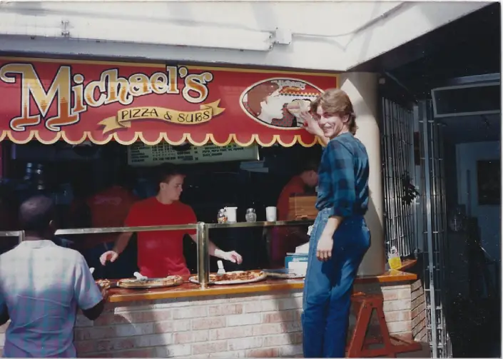 A woman standing in front of a food stand.