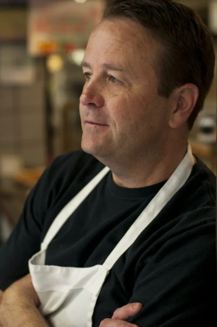 A man wearing an apron and looking to his left.
